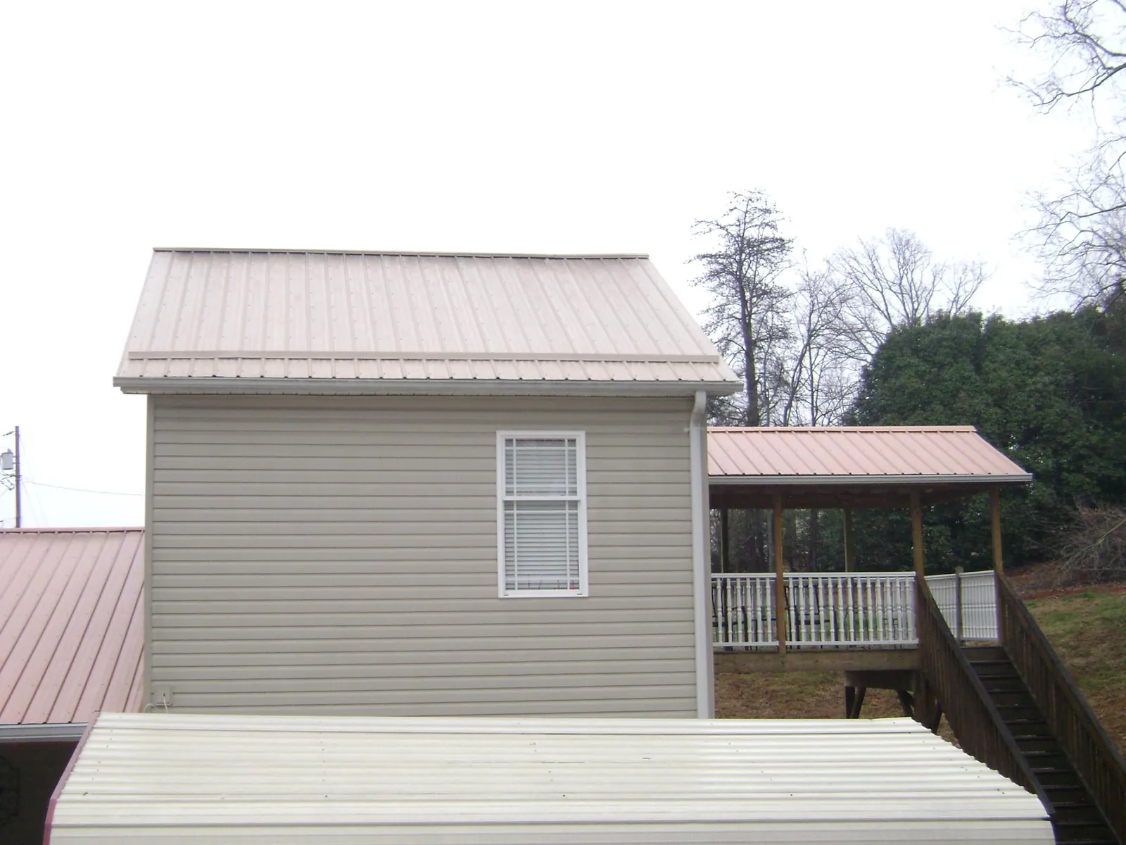 Tan metal roofs on a two story addition and attached porch, from a Roof Replacement job in Eaton